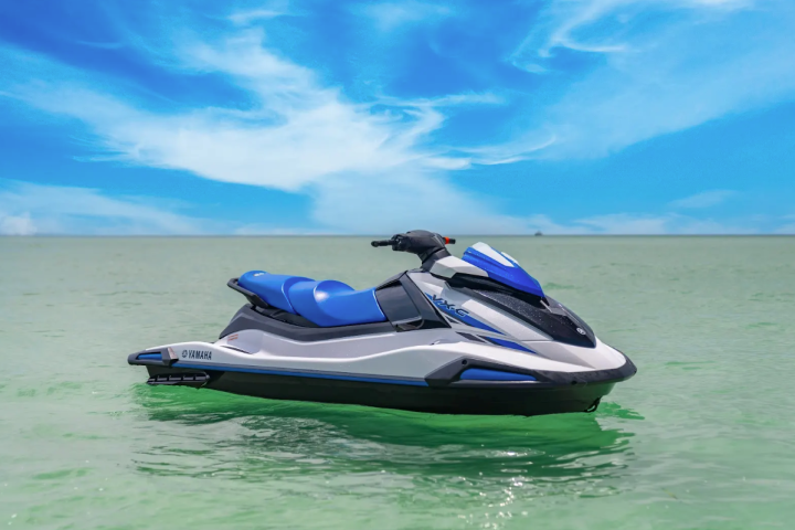 a blue and white boat sitting next to a body of water